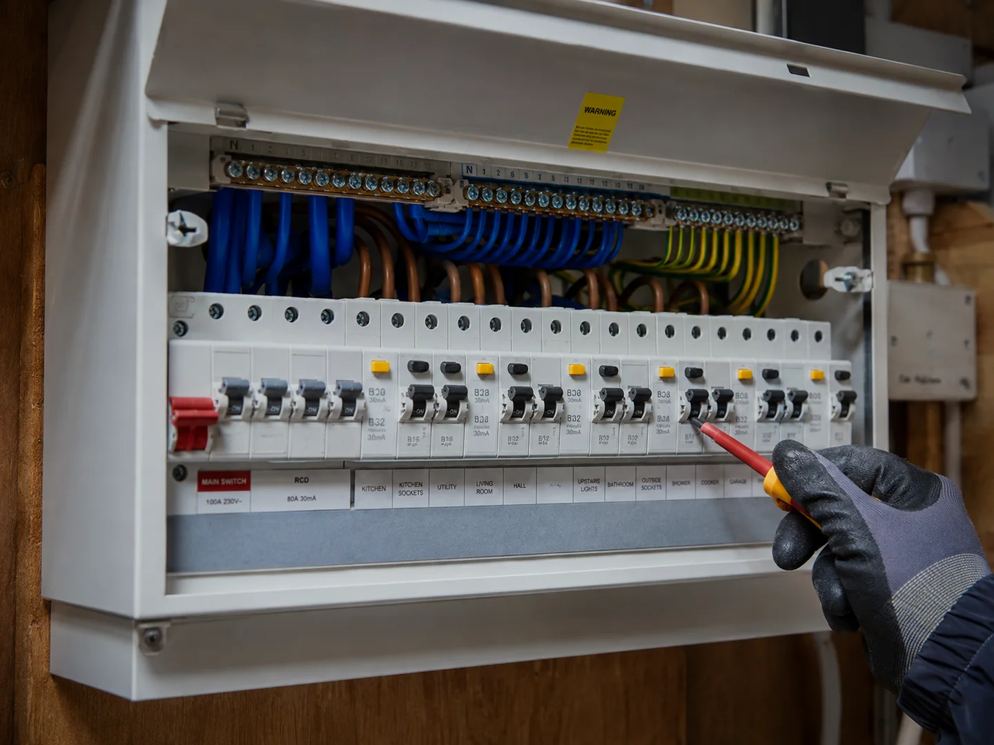 Modern UK consumer unit with tidy labelled cabling and an insulated tool.